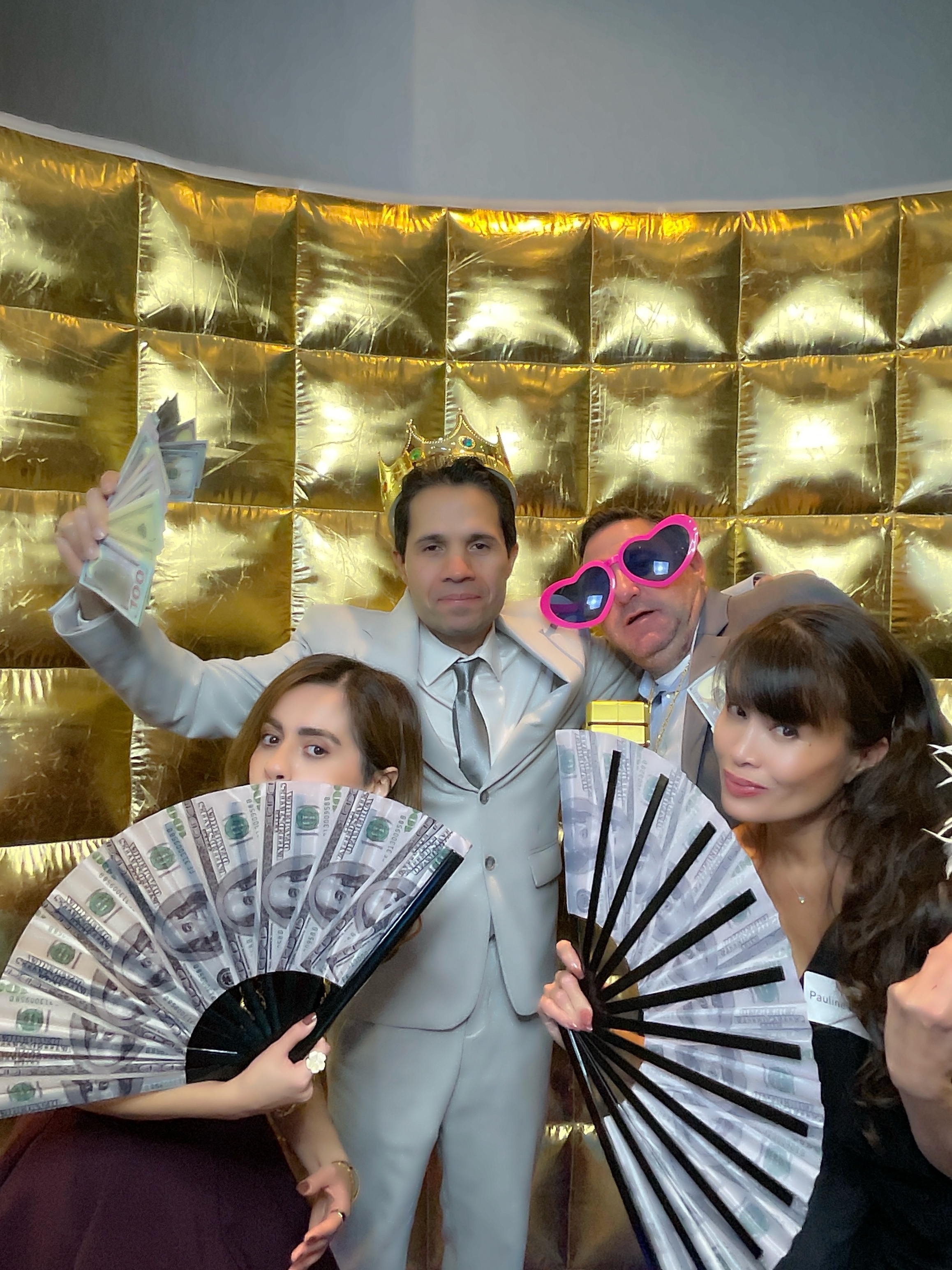 Guests posing with gold backdrop at a Liquid Gold photo booth event